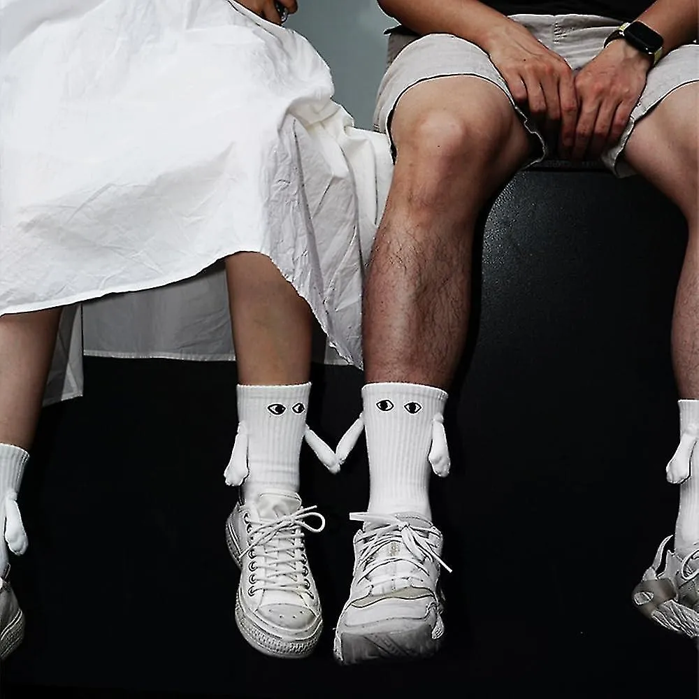 Calcetines magnéticos de mano que sostienen nuevos, calcetines de mano a mano, pareja que sostiene calcetines de manos